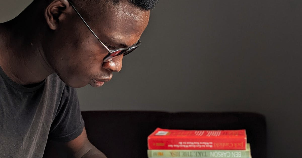 Young man studying intently with books in library setting.