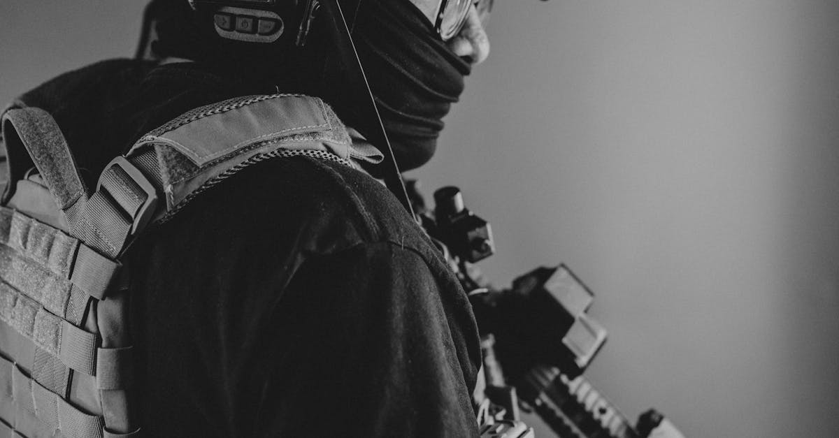 Black and white portrait of a soldier in tactical gear holding a rifle ready for action.